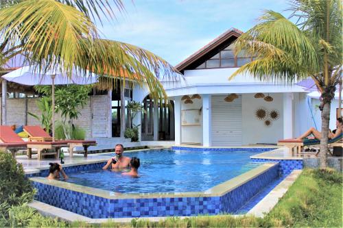 a family in a swimming pool in front of a house at Green Village Jungle Resort in Nusa Penida