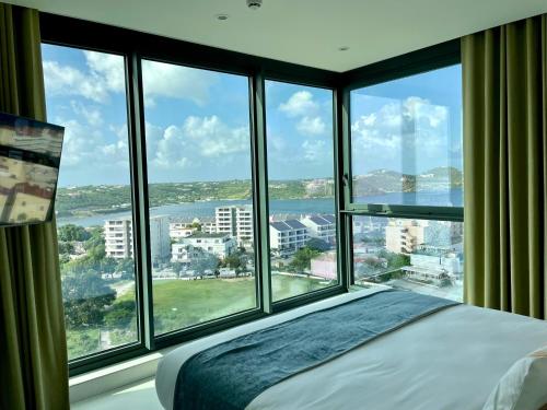 a bedroom with large windows with a view of the water at Gorgeous 2 bedroom, 17th floor, with breathtaking view, Fourteen at Mullet Bay in Cupecoy