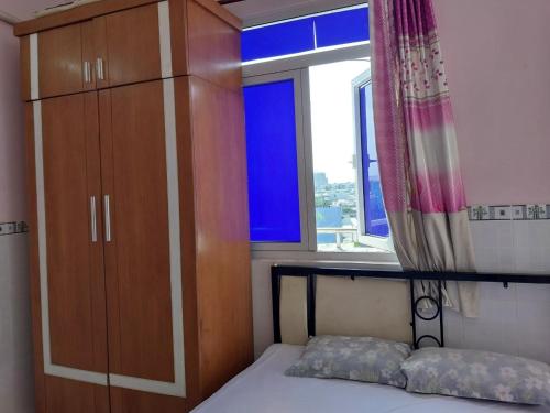 a bedroom with a bed and a cabinet and a window at Ngọc Mơ Motel in Ho Chi Minh City