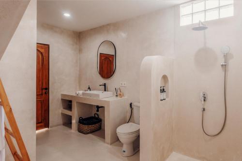 Un baño con lavabo, inodoro y espejo. en Casa Cherish 2 BR Canggu Villa, en Canggu