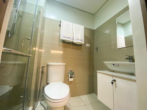 a bathroom with a toilet and a shower and a sink at Homefort at S Residences in Manila
