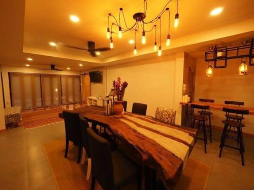 a dining room with a large wooden table with chairs at Rock Garden Beach D19 Pool Villa in Rayong