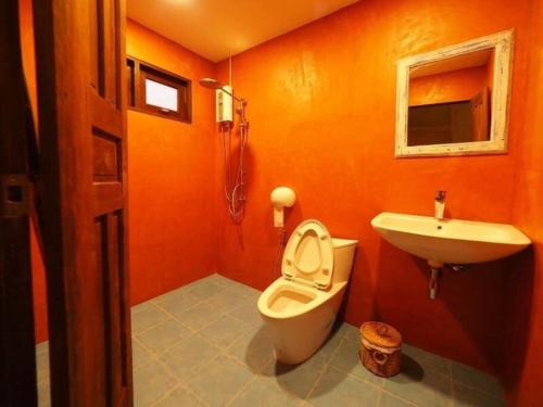 an orange bathroom with a toilet and a sink at Rock Garden Beach D19 Pool Villa in Rayong