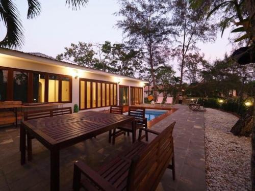 a patio with a wooden table and benches next to a house at Rock Garden Beach D19 Pool Villa in Rayong