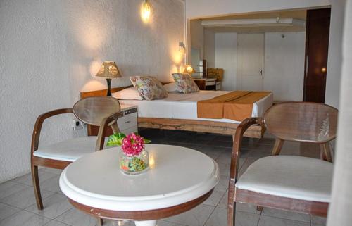 a hotel room with a bed and a table and chairs at Le Recif Hotel Rodrigues in Rodrigues Island