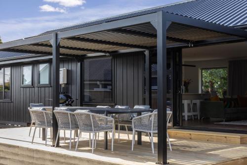 a pergola with chairs and a table on a deck at The Corner on Te Mata in Havelock North