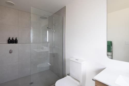 La salle de bains blanche est pourvue d'une douche et de toilettes. dans l'établissement The Corner on Te Mata, à Havelock North