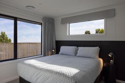 北哈夫洛克的住宿－The Corner on Te Mata，一间卧室设有一张床和两个窗户。