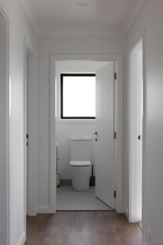 a white bathroom with a toilet and a window at The Corner on Te Mata in Havelock North