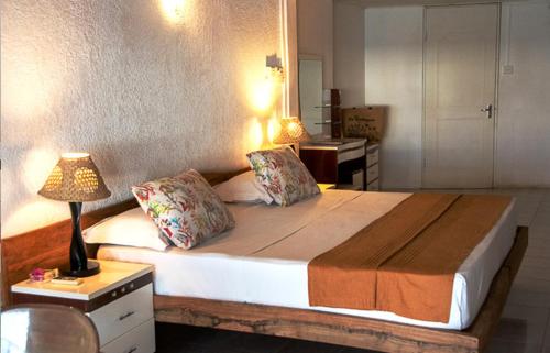 a bedroom with a large bed with a lamp on a table at Le Recif Hotel Rodrigues in Rodrigues Island
