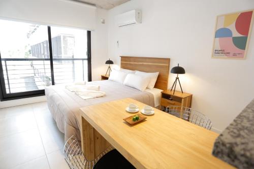 a bedroom with a bed and a wooden table at OWN Belgrano Studios & Suites in Buenos Aires
