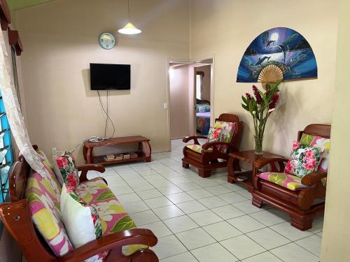 a living room with couches and a tv at Sharnyta’s Guesthouse in Avarua