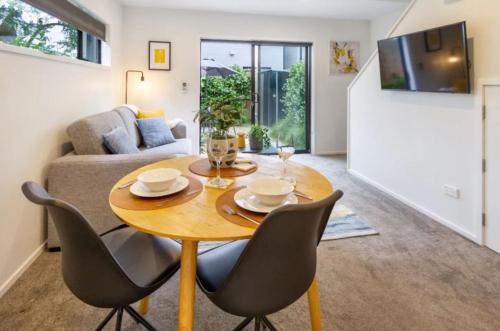 a living room with a wooden table and chairs at Central City-Urban Oasis 1 bed 1 bath w/sofa bed in Christchurch