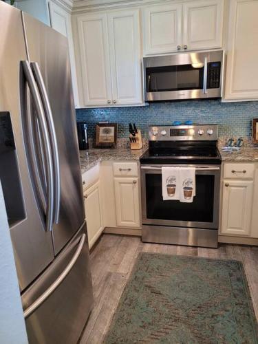 a kitchen with stainless steel appliances and white cabinets at Beach Condo on Okaloosa Island Emerald Isle 6th floor 2 bedrooms and murphy bed in Fort Walton Beach
