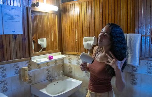 Eine Frau mit blauen Haaren steht in einem Badezimmer in der Unterkunft Le Recif Hotel Rodrigues in Rodrigues Island