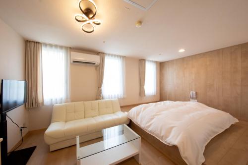 ein Schlafzimmer mit einem weißen Bett und einem Sofa in der Unterkunft Resort Hotel Tateshina in Chino