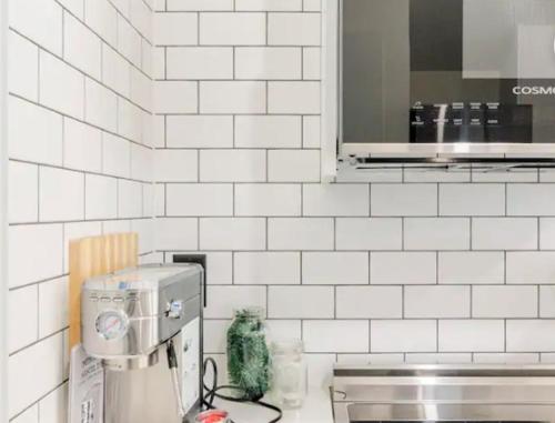 a white tiled kitchen with a counter with a coffee maker at Tiny House Haven in Peterborough