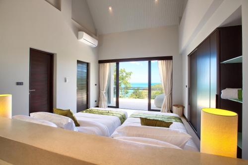 a room with four white couches and a large window at Villa Moonshadow - Multiple Award Winning Villa in Chaweng Noi Beach