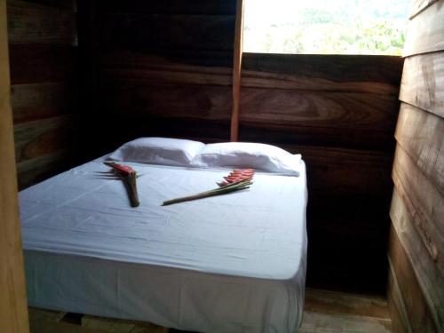 a bedroom with a bed with white sheets and two sticks at Posada la Ofelia in El Zaino