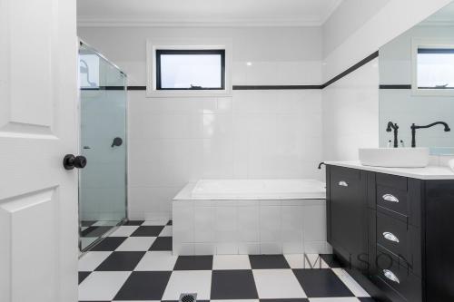 a white bathroom with a tub and a sink at Entire Home with Views and Heated Pool in Newcastle