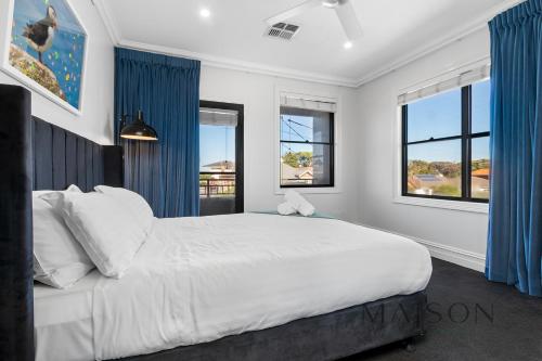 a bedroom with a large white bed with blue curtains at Entire Home with Views and Heated Pool in Newcastle