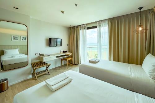 a hotel room with two beds and a mirror at Zand Morada Pattaya in Jomtien Beach