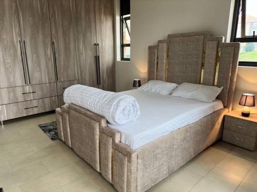 een slaapkamer met een groot bed met witte lakens bij Heavenly Getaways, Nalya in Kampala