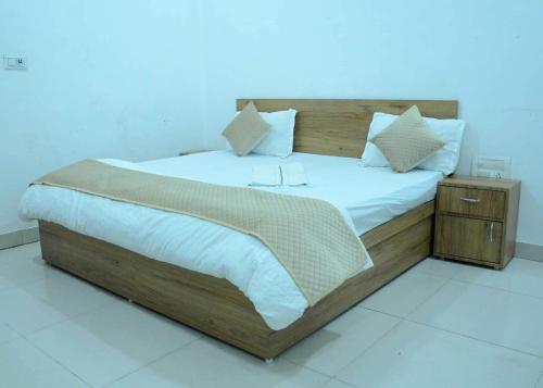 Un dormitorio con una gran cama de madera con sábanas blancas. en OYO HOTEL GREEN, en Jīnd