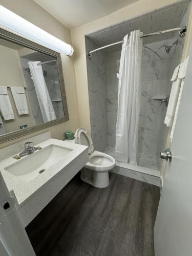 a bathroom with a sink and a toilet and a shower at James River Inn & Suites in Newport News