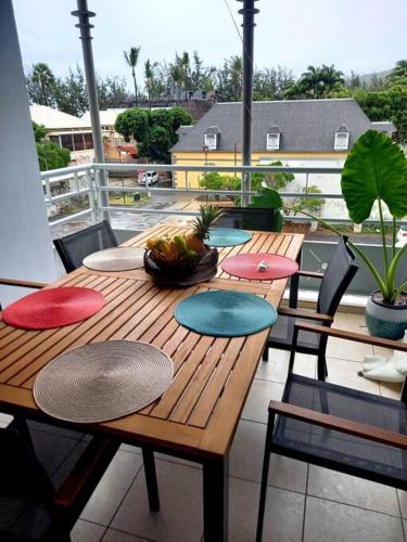 y balcón con mesa y sillas de madera. en Appartement la marine, en Saint-Leu