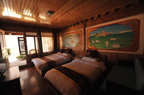Tibet Guesthouse 虎跳峡卓玛客栈 في شانغريلا: غرفه بثلاث اسره ولوحه على الحائط