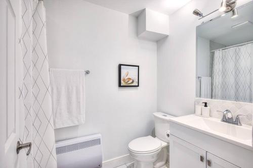 a white bathroom with a toilet and a sink at Charming 2BR with Balcony in Montreal in Montreal