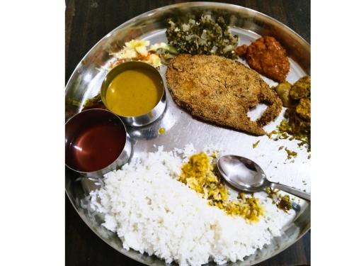 a plate of food with rice and bread and two spoons at Cockerel Homestay - Traditional Beach Village - Goa in Canacona
