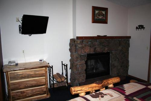 a living room with a stone fireplace and a television at Timber Creek Chalets- 4 chalet in Estes Park