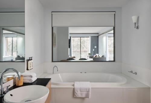 a white bathroom with a tub and a large mirror at RACV Goldfields Resort in Ballarat