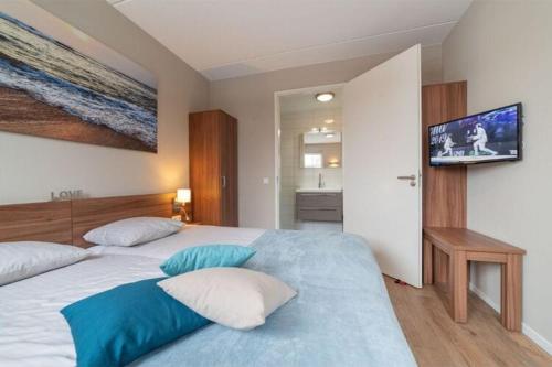 a bedroom with a large bed with blue and white pillows at Detached family friendly villa in the Oosterschelde National Park in Colijnsplaat