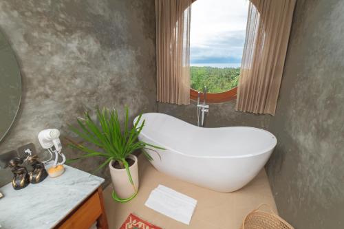 a bathroom with a white bath tub and a window at Villa Kaliente in Nusa Penida