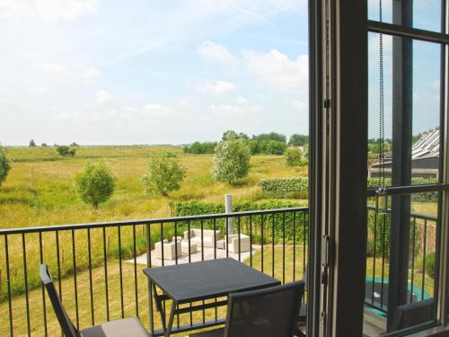 a balcony with a table and chairs and a view of a field at Premium apartment with private wellness in Zeeland in Colijnsplaat