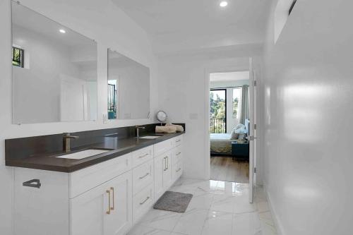 a white kitchen with a sink and a mirror at Mesmerizing Villa. Perfect for group retreats in Los Angeles