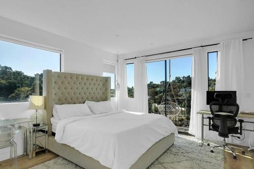 a white bedroom with a bed and a desk and windows at Luxury hilltop retreat, majestic views and hot tub in Los Angeles