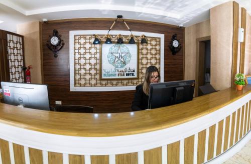 a woman sitting at a counter in an office at Diamond Star Hotel فندق النجمة الماسية in Seeb