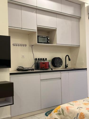 a white kitchen with white cabinets and a microwave at Hello studio in Noida