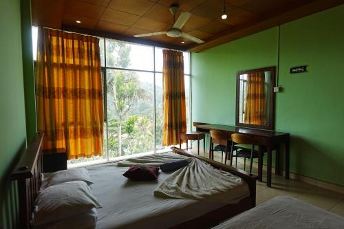 a bedroom with a bed and a desk and a window at Suisse View Residence Kandy in Kandy