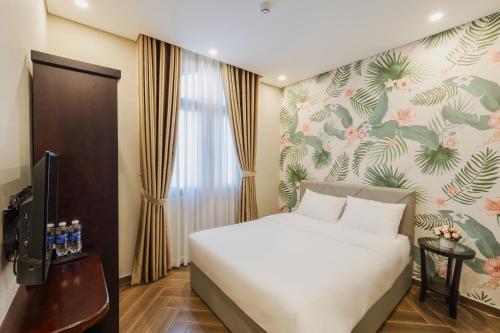 1 dormitorio con cama blanca y pared de flores en Tropical Bay Grand World Phu Quoc, en Phu Quoc