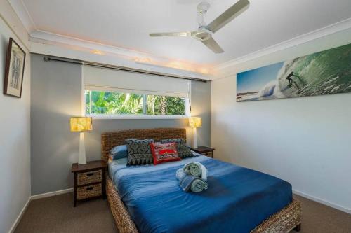 Schlafzimmer mit einem Bett mit blauer Bettwäsche und einem Fenster in der Unterkunft Enchanted Garden Cottage with Bikes in Russell Island