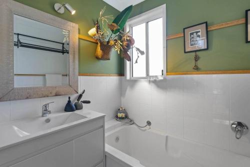 ein Bad mit einem Waschbecken, einer Badewanne und einem Fenster in der Unterkunft Enchanted Garden Cottage with Bikes in Russell Island