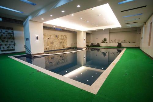 a swimming pool with a green floor in a building at Simple Ortigas Suite w/ City View, & Pool 3017 in Manila