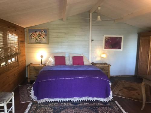1 dormitorio con 1 cama de color púrpura y 2 mesitas de noche en Casa del Paso, en Bolulla