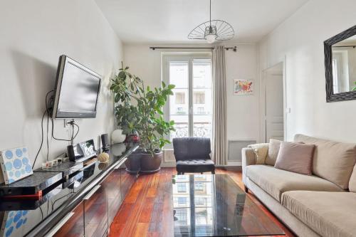 - un salon avec un canapé et une télévision dans l'établissement Charming apartment in Courbevoie - Welkeys, à Courbevoie