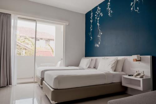 ein Schlafzimmer mit zwei Betten und einer blauen Wand in der Unterkunft Cozy Stay Bali by ARM Hospitality in Seminyak